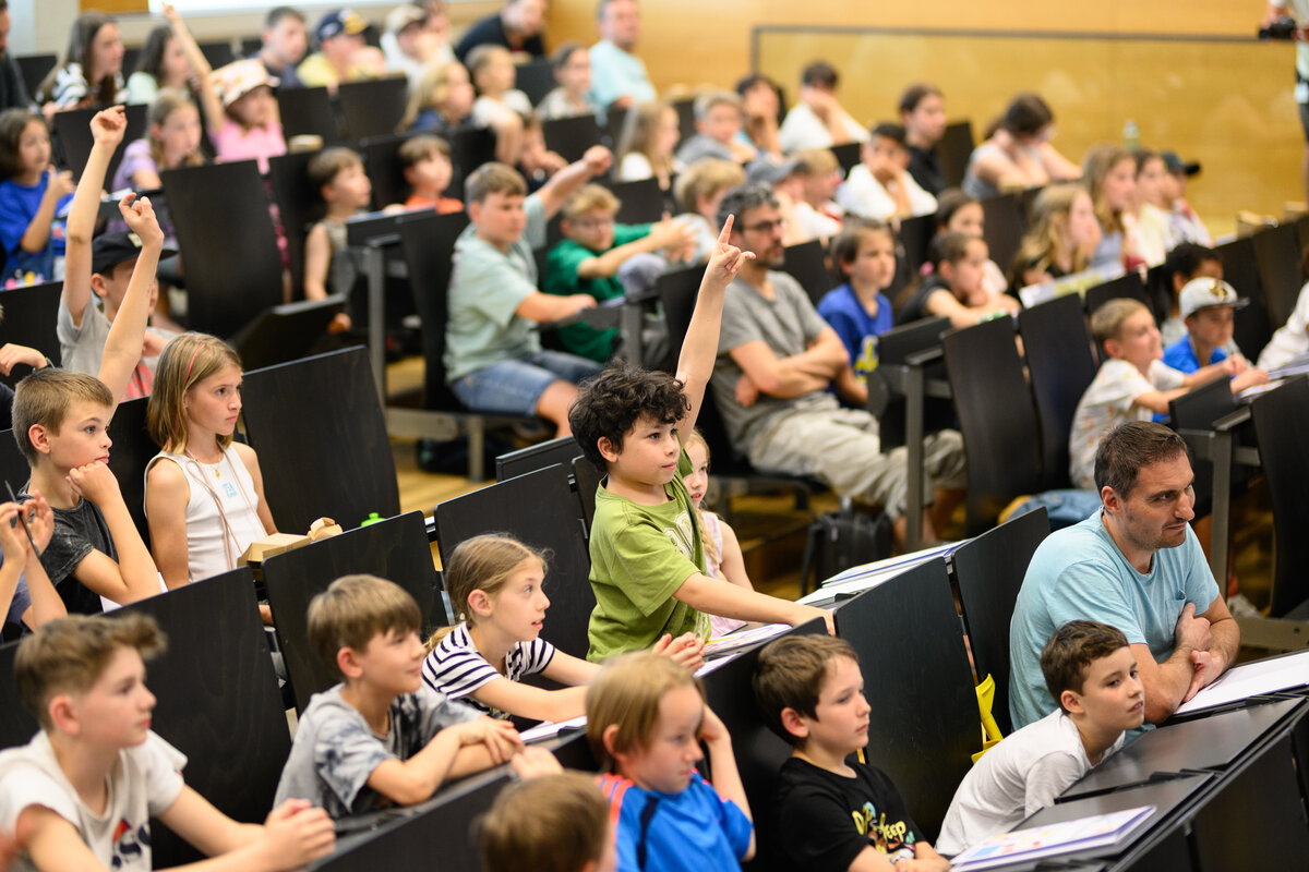 Kinder zeigen in der Kinder Uni auf und machen mit beim Vortrag.  | © FHV / Mattias Rhomberg