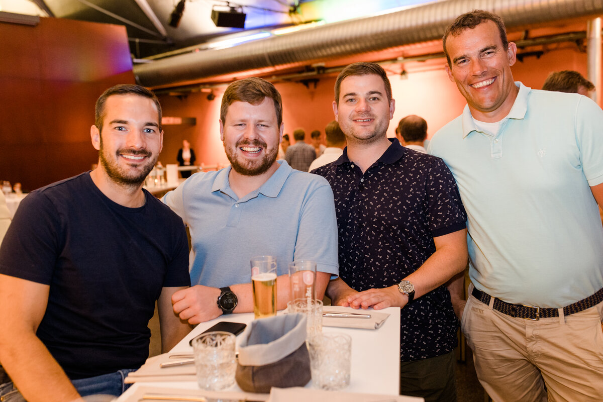 Bild von vier Absolventen der FHV beim Alumni Day 2022. Sie lachen in die Kamera. | © Nina Bröll & FHV