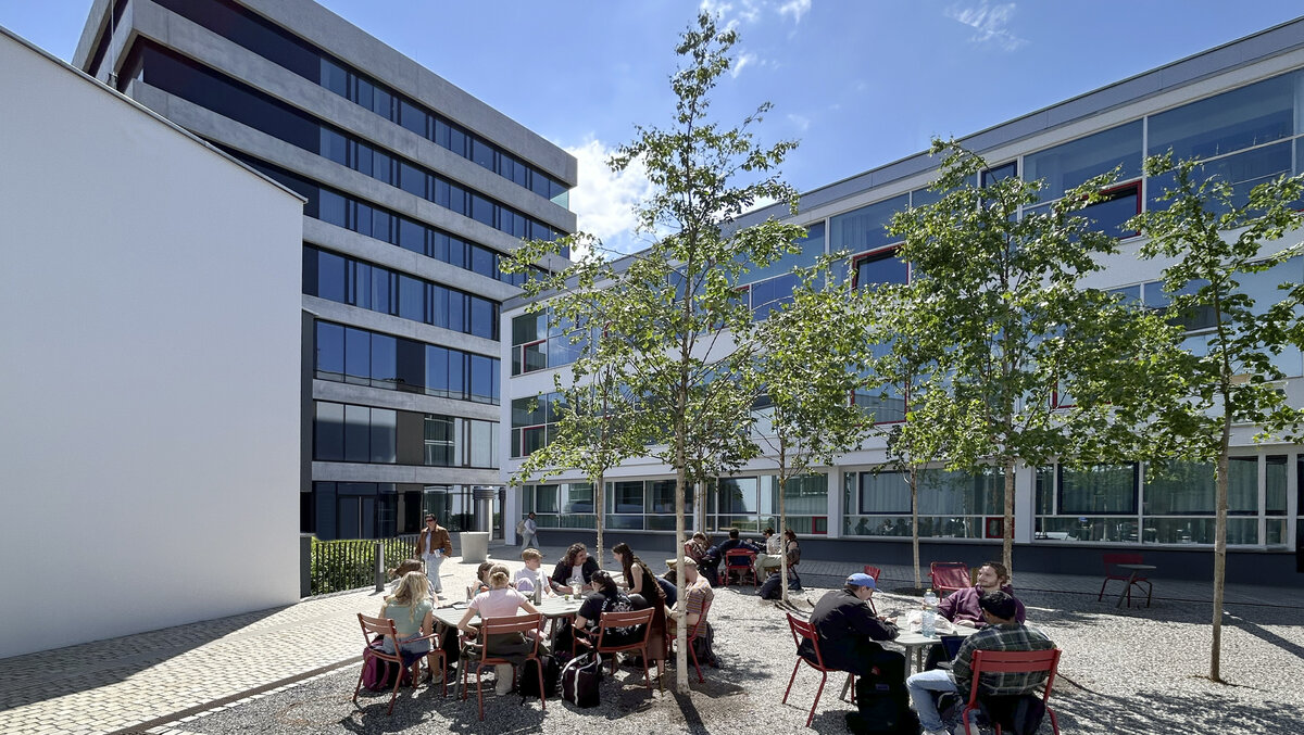 Studierende sitzen im FHV Campushof zwischen den Gebäuden C, E und G | © FHV