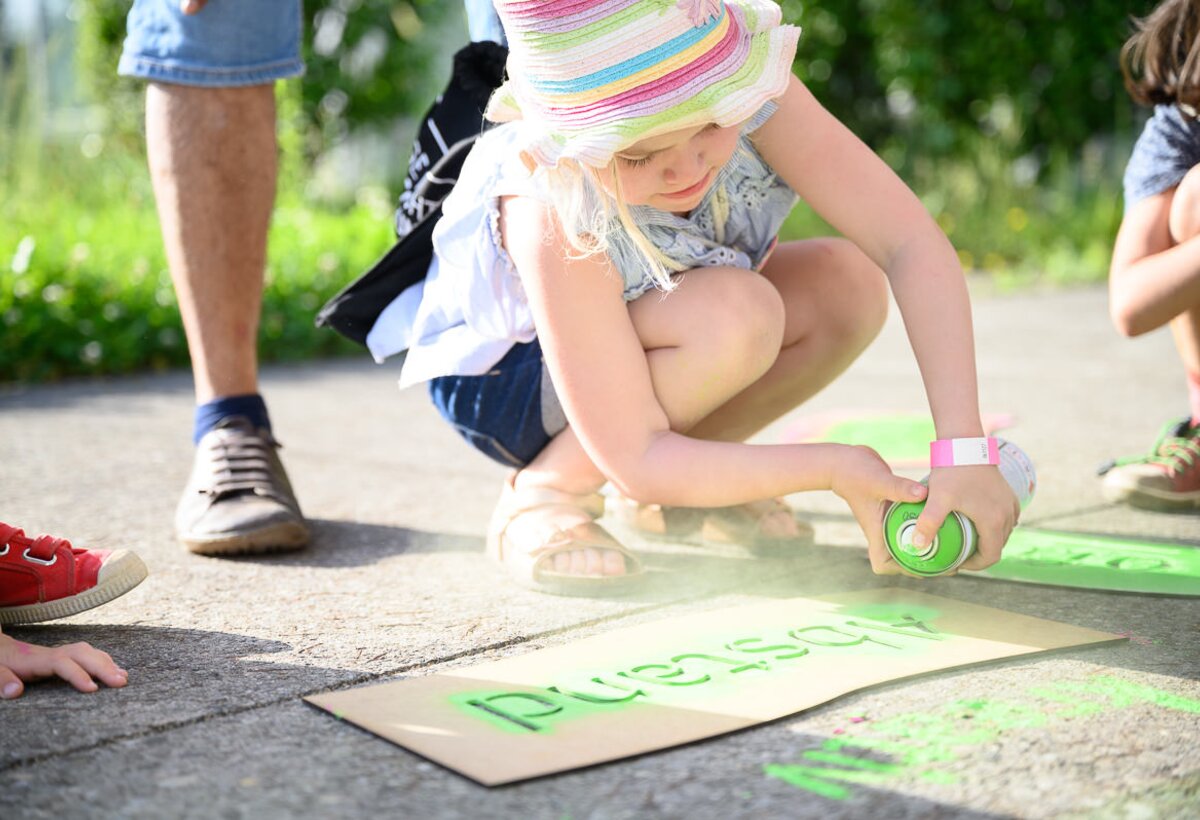 Kleines Mädchen sprayt grüne Farbe auf Asphalt | © ©-MATTHIAS-RHOMBERG