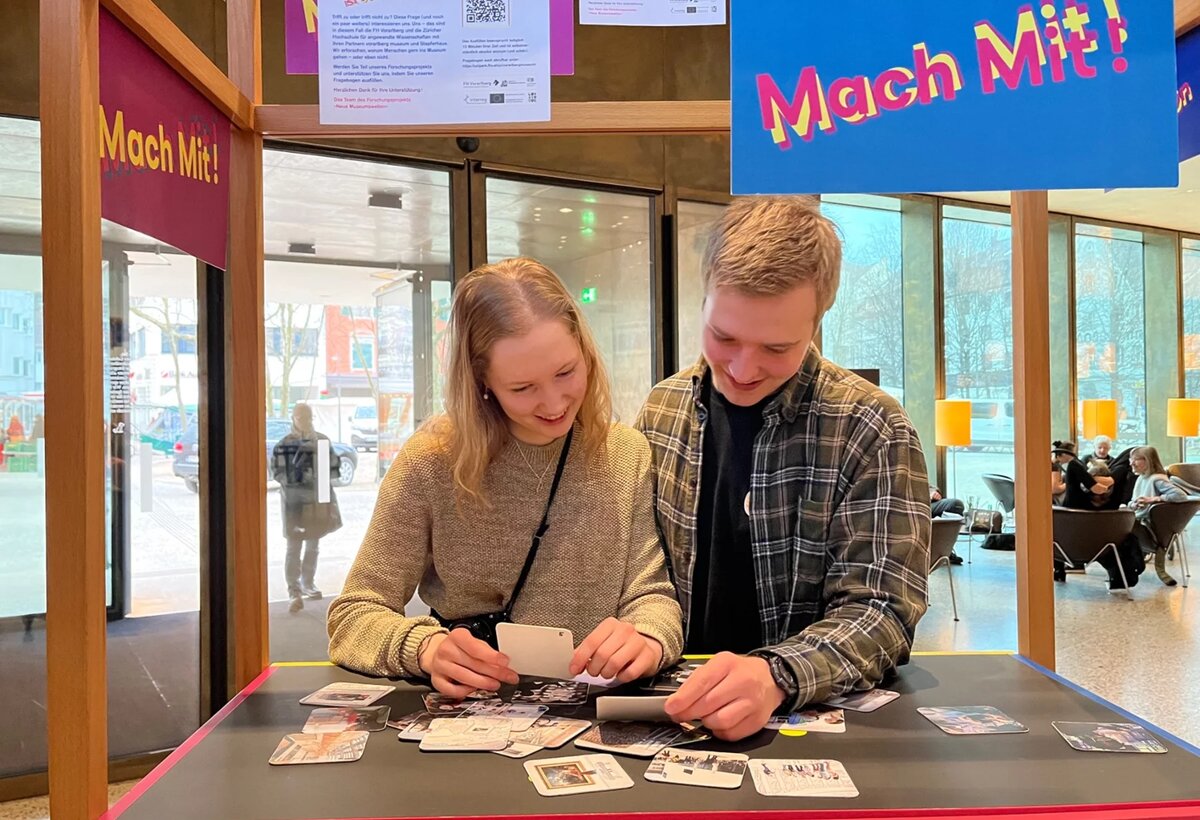 New museum worlds 04 | © FHV Two people are standing at a stand and playing cards | © FHV