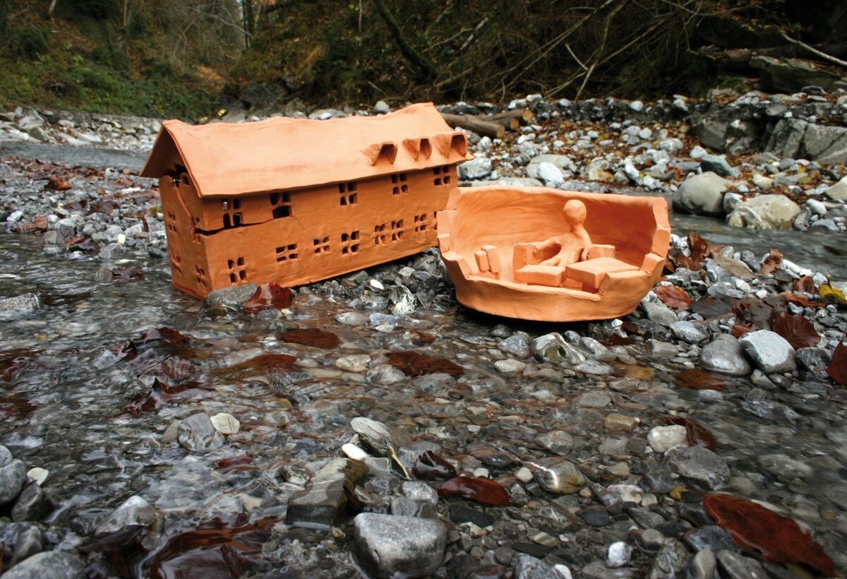 Bach mit fliessendem Wasser sowie einem Miniaturtonhaus und einer Miniaturtonperson