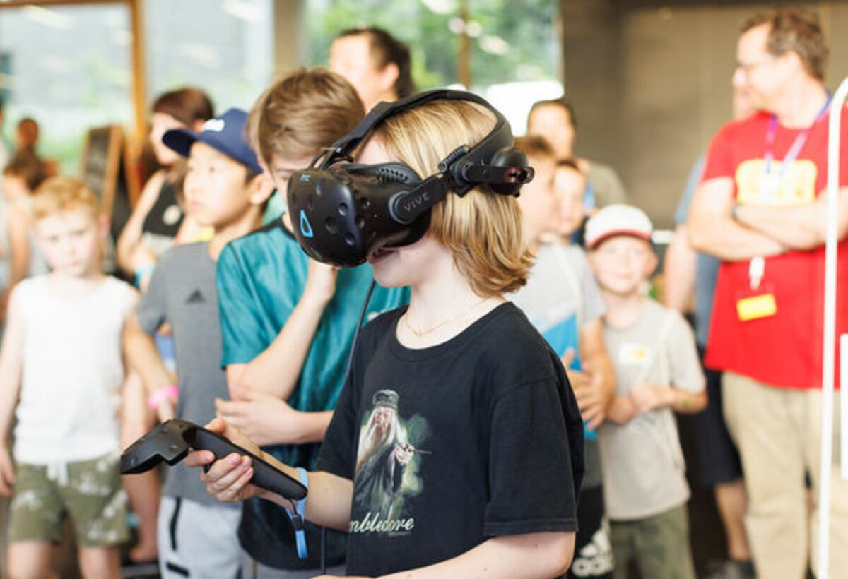 Das Bild zeigt ein Junge mit einer VR-Brille und einem Joystick.