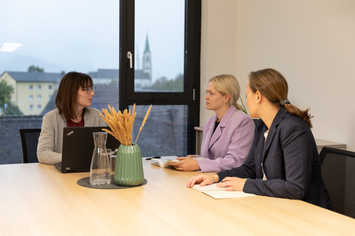 Drei Frauen sitzen in einem Büro an einem Tisch und besprechen sich. | © WISTO: Belinda Konzett