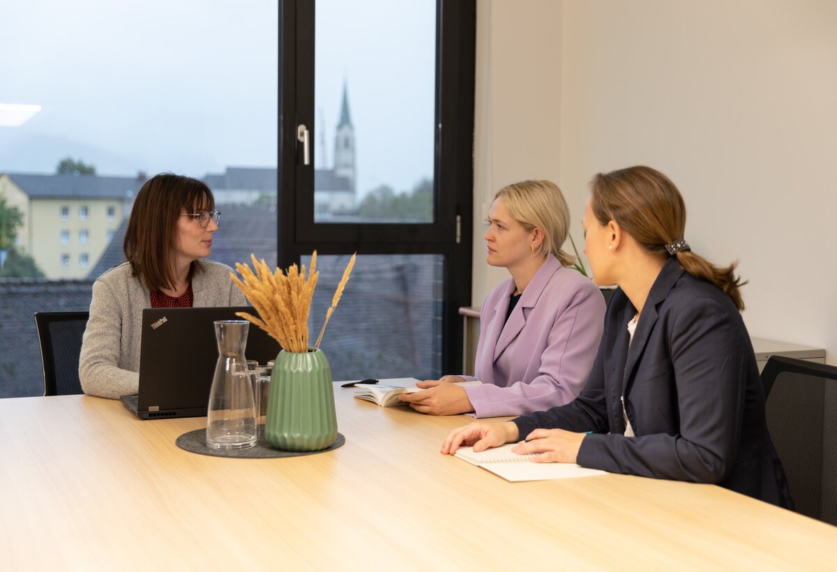Drei Frauen sitzen in einem Büro an einem Tisch und besprechen sich. | © WISTO: Belinda Konzett