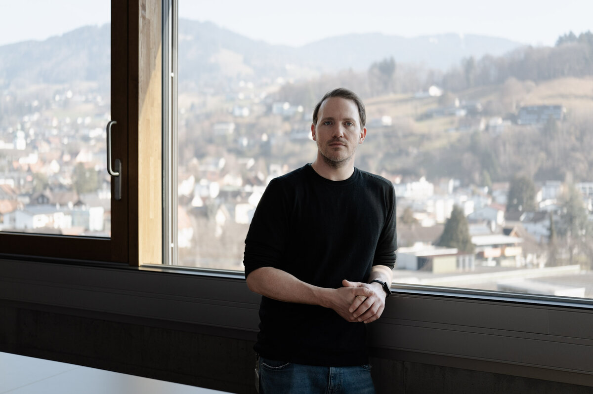 Michael Hellwig am Fenster mit Blick auf das Bergpanorama von Dornbirn. | © FHV