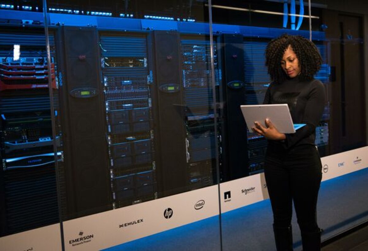 Frau mit Notebook vor einem Serverschrank