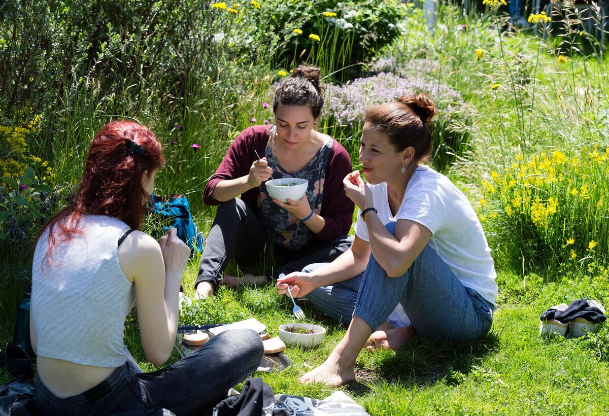 Menschen sitzen im Gras in einem Kreis und essen.