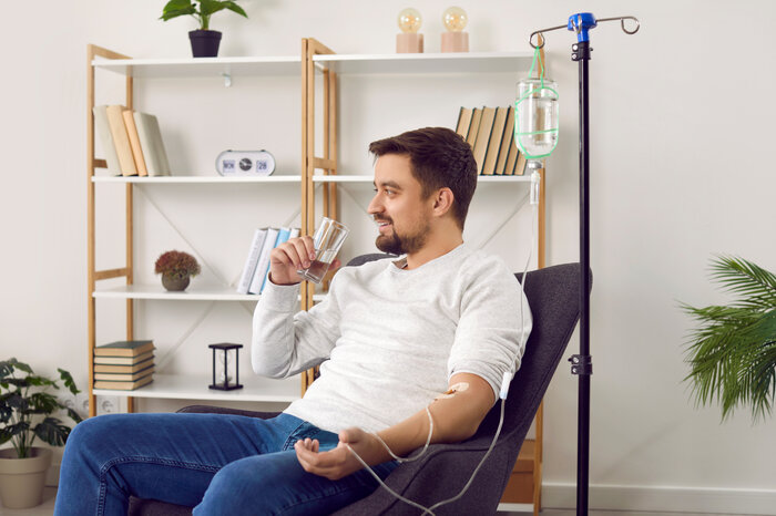 Mann bekommt im Wohnzimmer eine Infusion. | © Studio Romantic