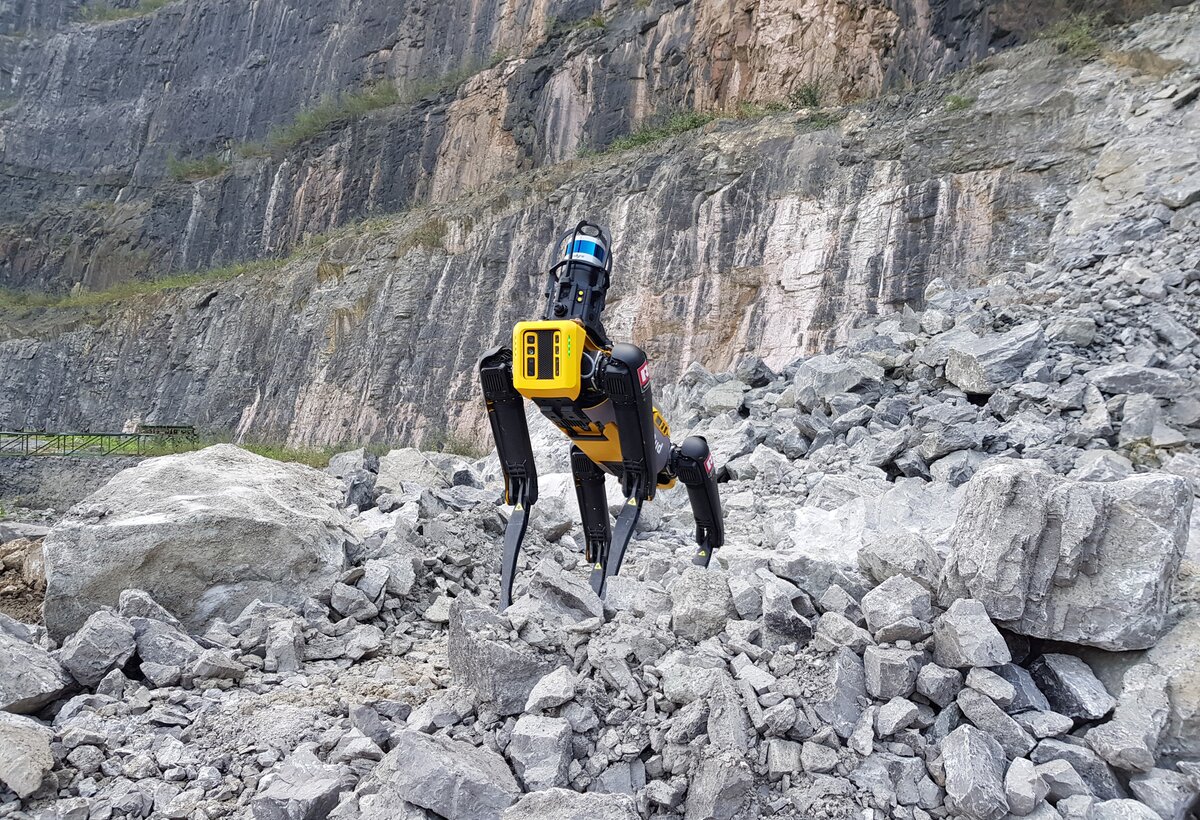 Roboterhund SPOT steht zwischen großen Steinen im Bergbau | © Rhomberg Sersa Rail Group