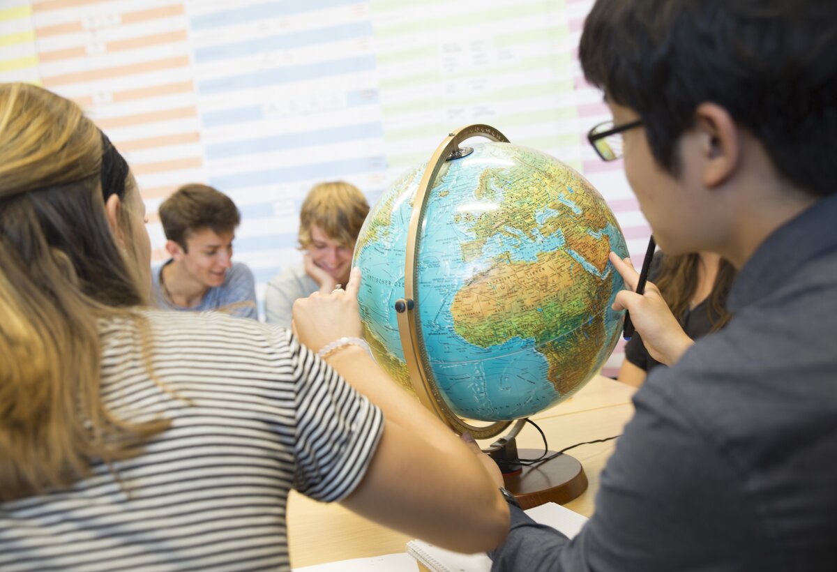 Students sit in front of a globe  | © FHV