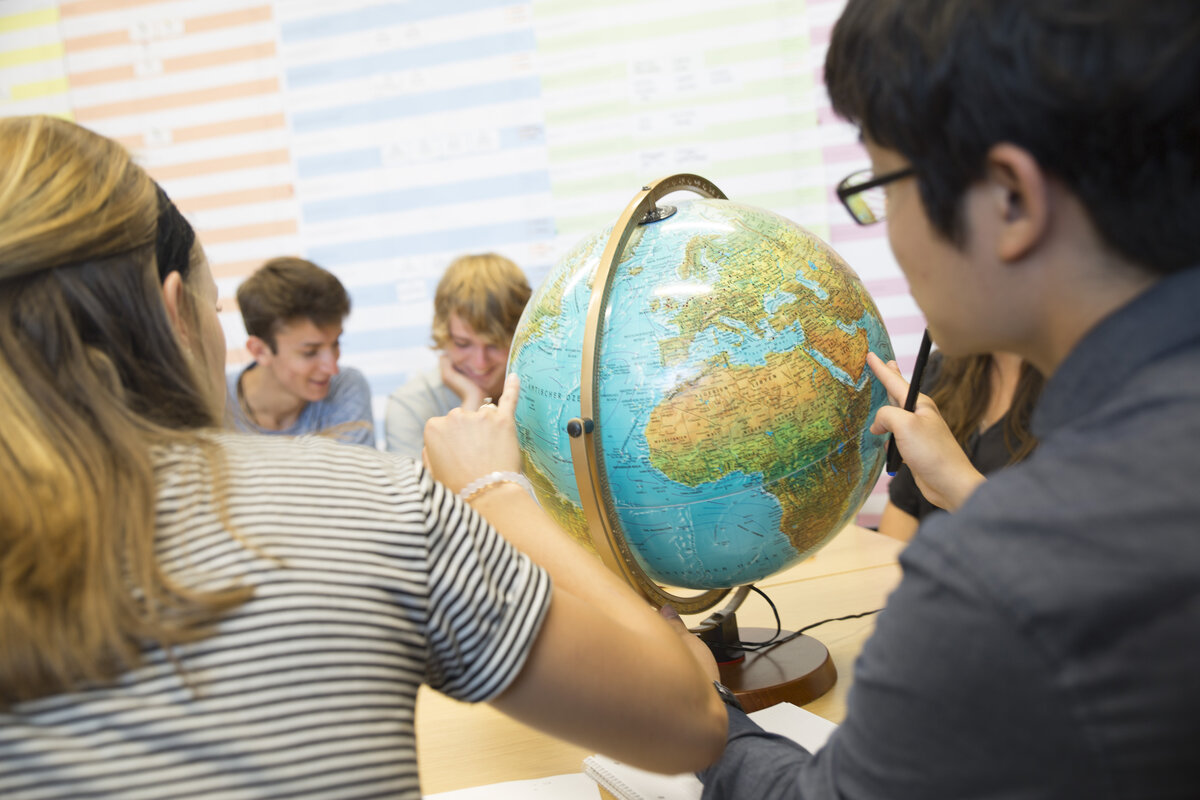 Studierende sitzen vor einem Globus  | © FHV