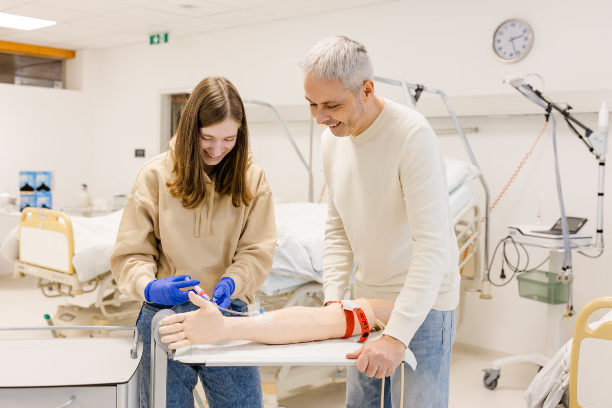 GKP-Student zeigt einer Studierenden, wie man eine Infusion gibt. | © Nina Bröll / FHV