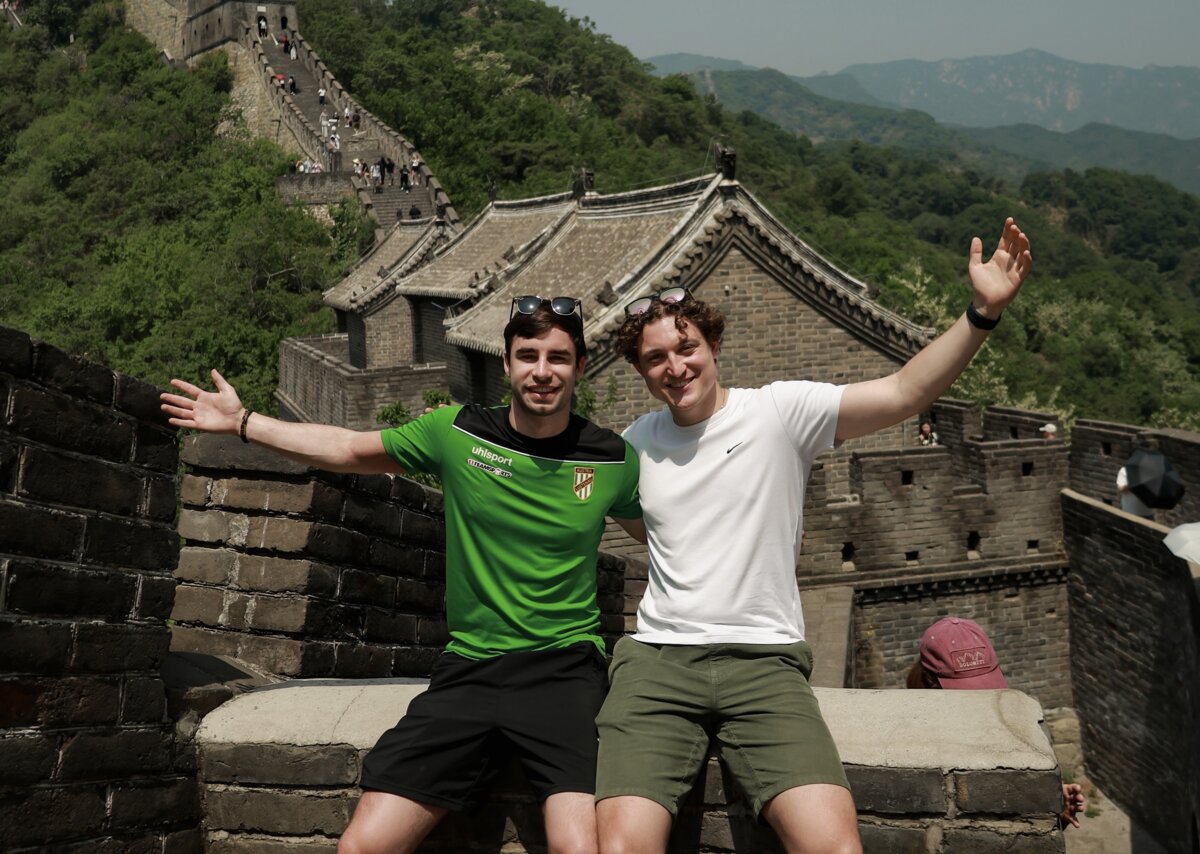 Die Studenten sitzen auf einer Mauer. Im Hintergrund sieht man die chinesische Mauer. | © privat