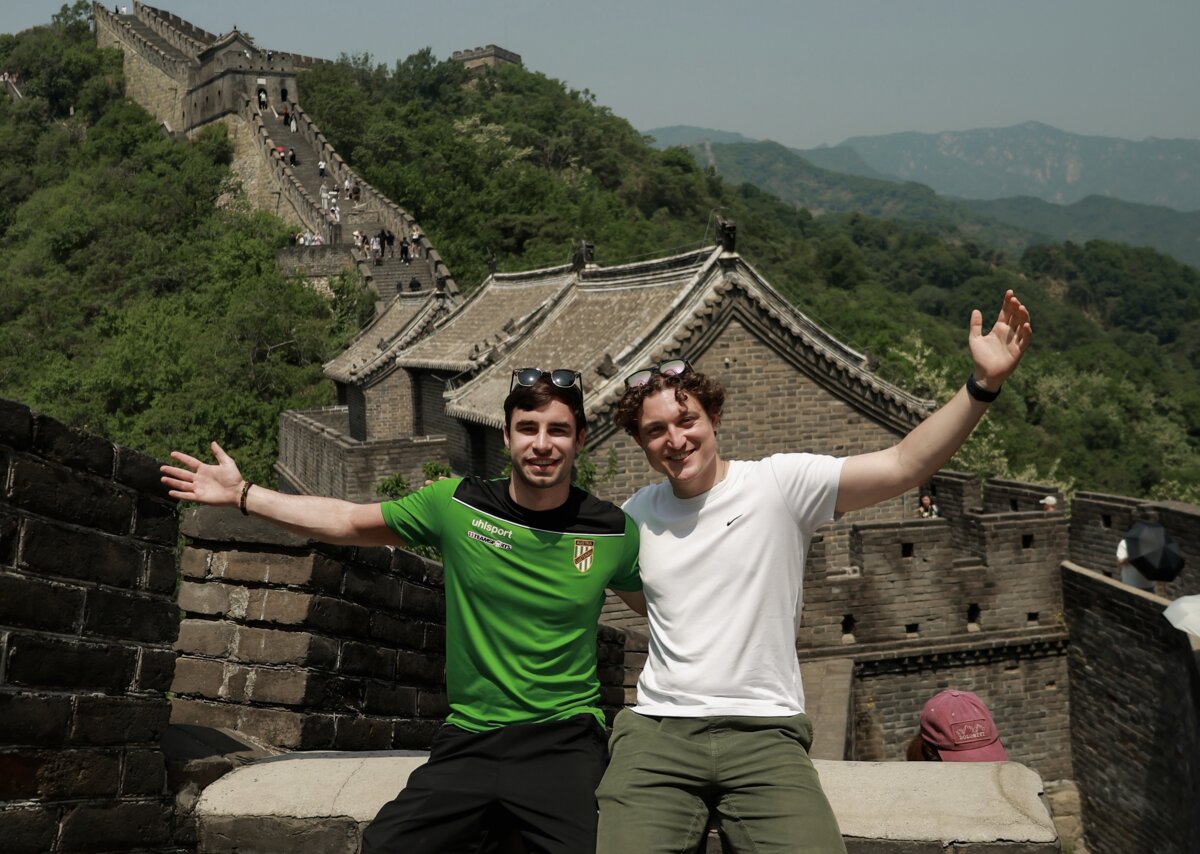 Die Studenten sitzen auf einer Mauer. Im Hintergrund sieht man die chinesische Mauer. | © privat