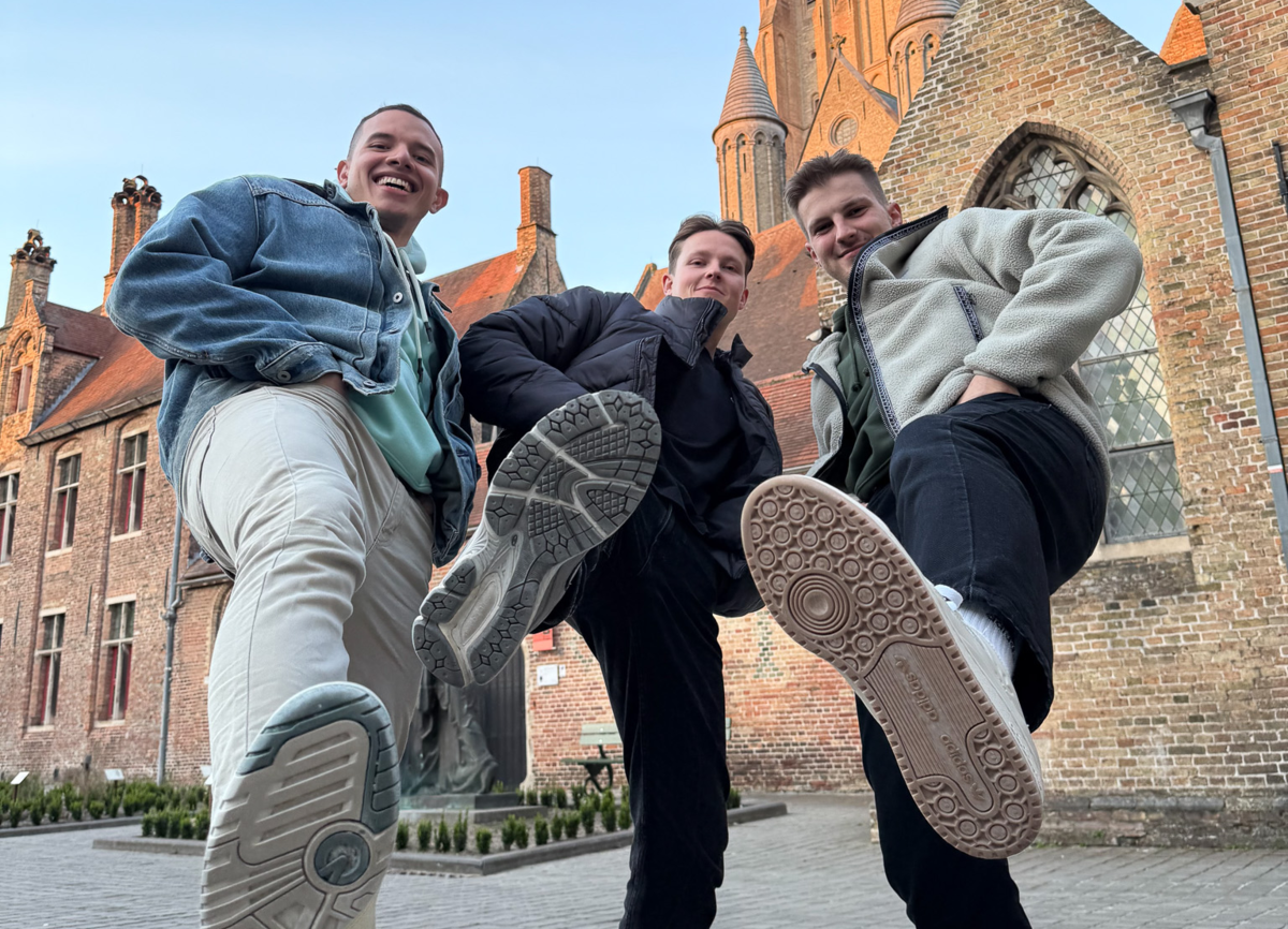 Nick Hämmerle with two friends, posing confidently for the camera in front of a red brick building at HOWEST University of Applied Sciences in Belgium. They look relaxed and happy, capturing a fun moment during their exchange programme. | © Privat