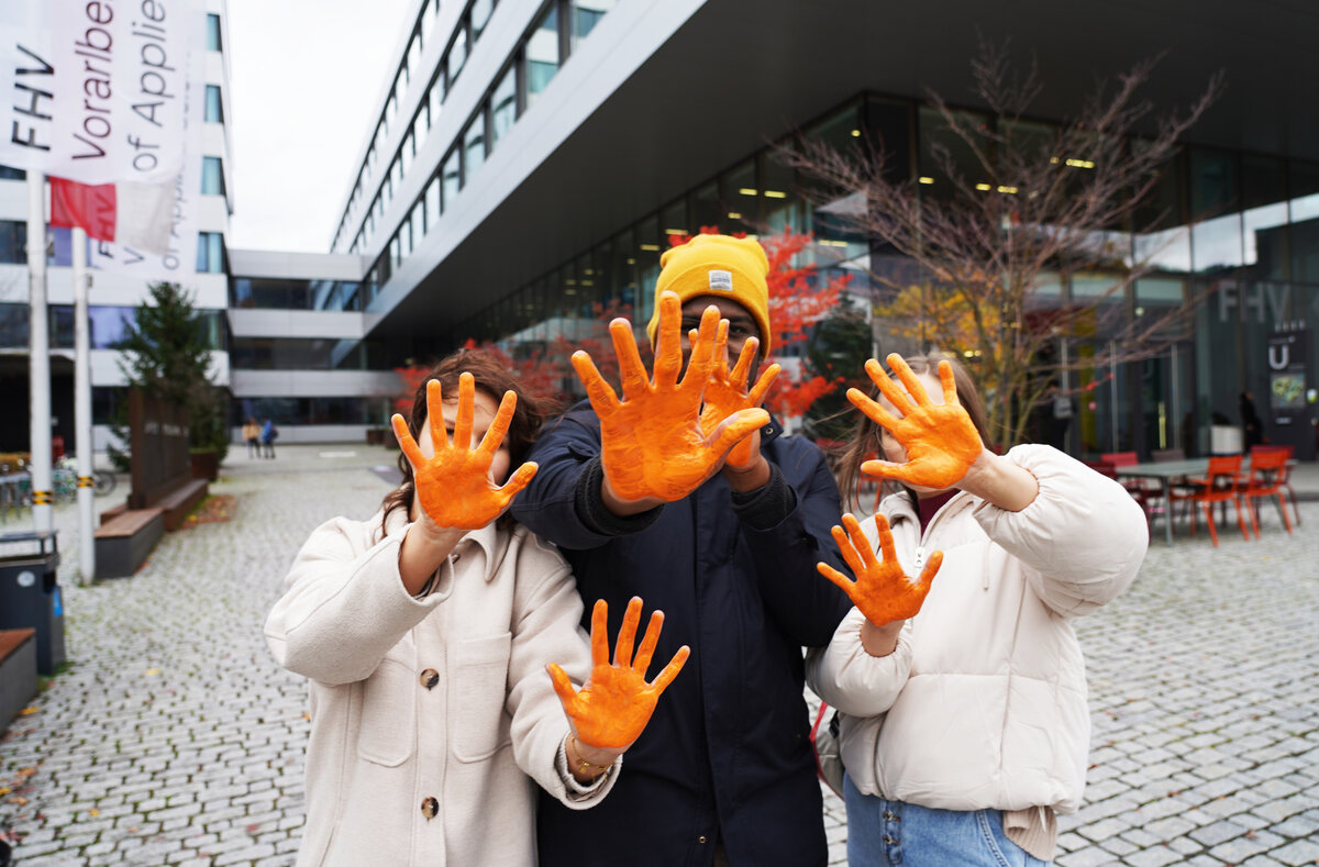 Drei Studierende halten ihr orangegefärbten Hände in die Kamera | © FHV