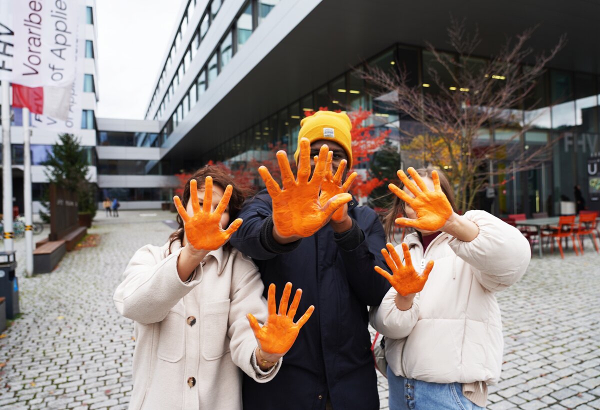 Drei Studierende halten ihr orangegefärbten Hände in die Kamera | © FHV