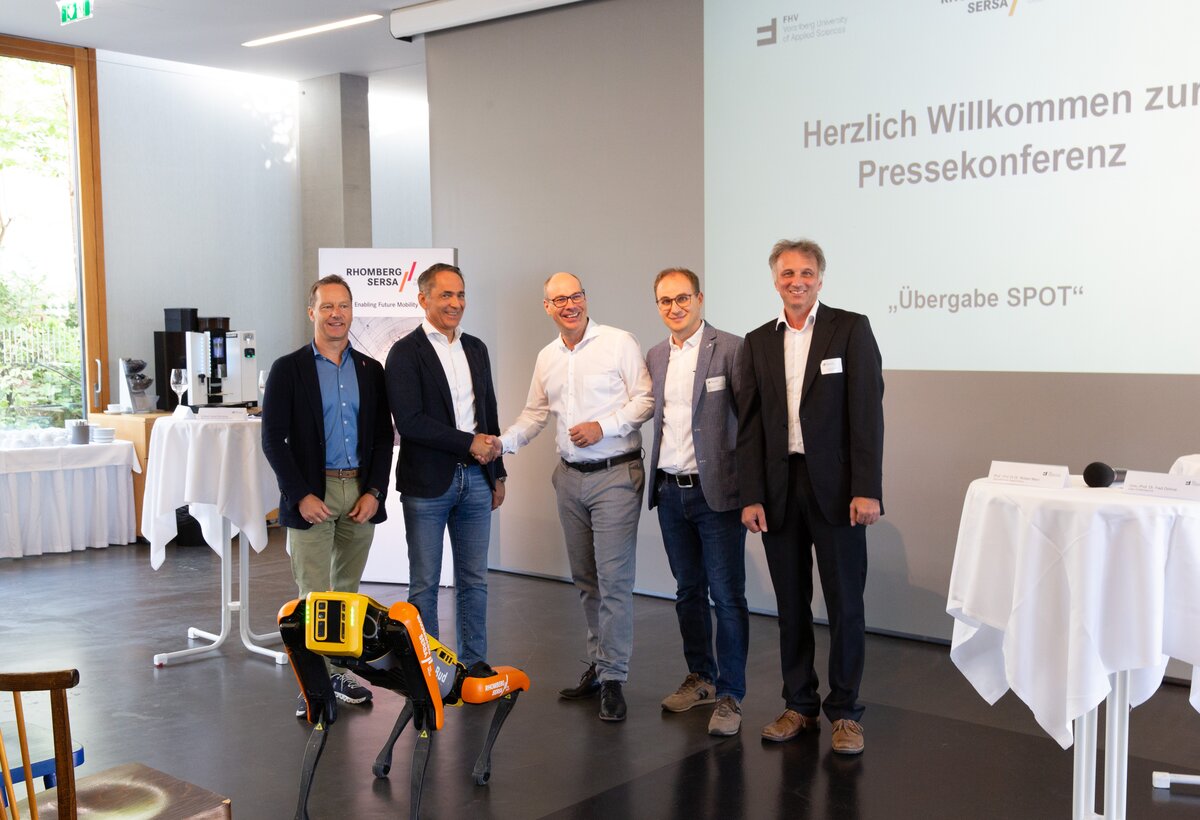 Pressekonferenz Uebergabe Spot Roboterhund Hubert Rhomberg, Garry Thür, Stefan Fitz-Rankl, Robert Merz, Fadi Dohnal | © Rhomberg Sersa Rail Group Pressekonferenz mit fünf Personen an der FH Vorarlberg | © Rhomberg Sersa Rail Group
