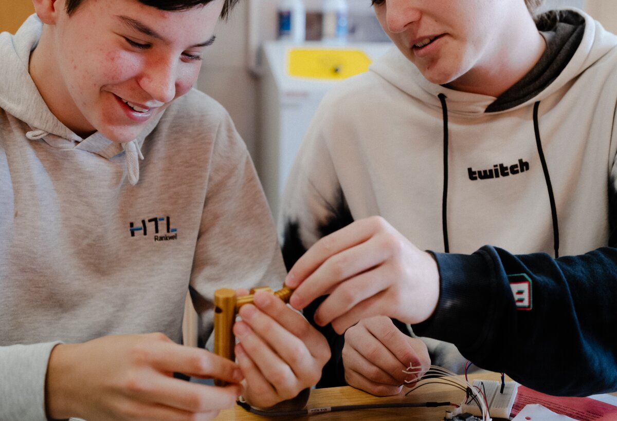 Leo (links, BG Dornbirn) und Raphael (rechts, HTL Rankweil) halten einen 3D-gedruckten Prototypen zur Schallreduktion in der Hand, freuen sich und diskutieren über Verbesserungen. | © FHV Zwei Schüler halten einen 3D-gedruckten Prototypen zur Schallreduktion in der Hand | © FHV