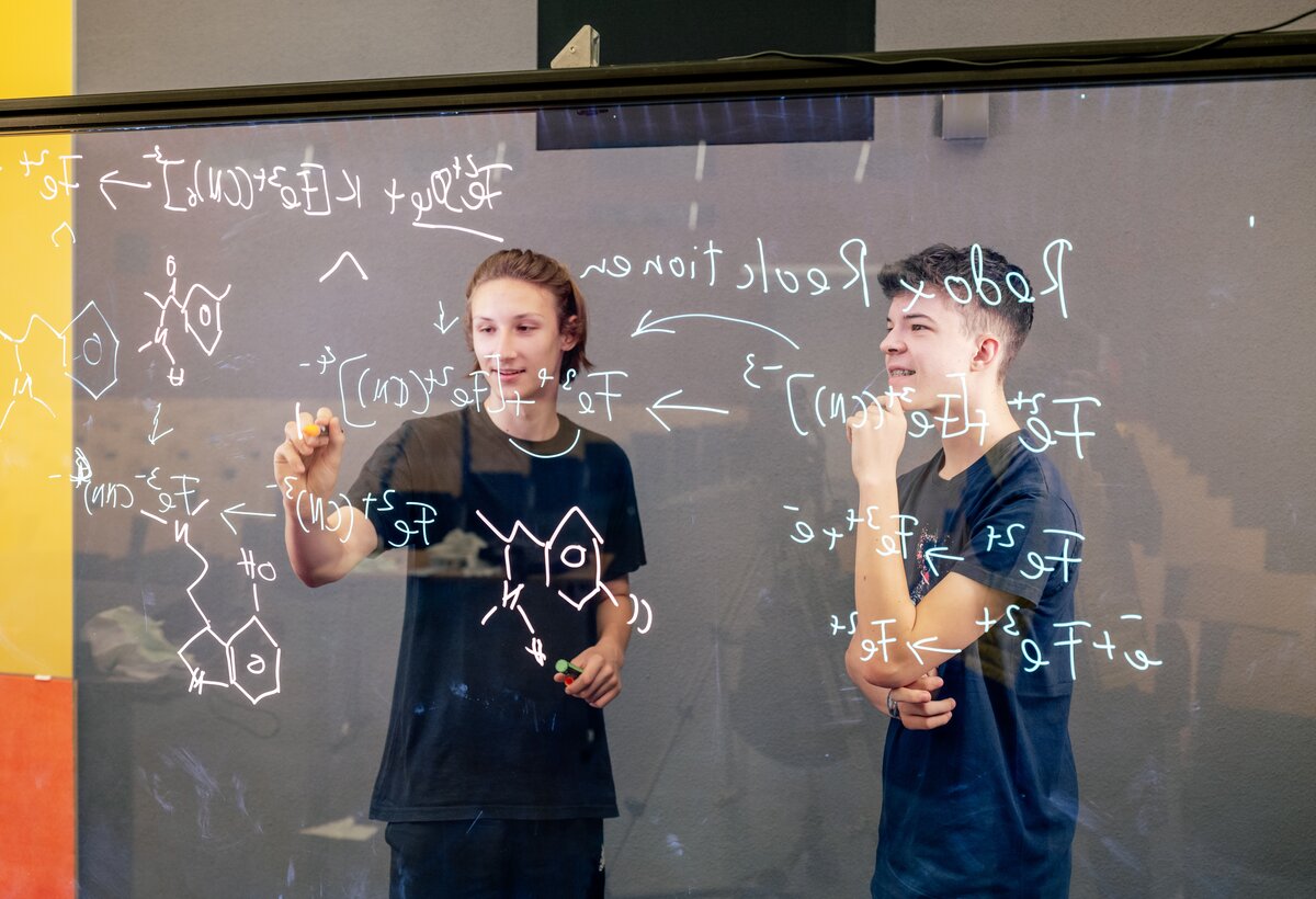 Zwei Schüler diskutieren hinter dem selbst aufgebauten Lightboard über Chemieformeln | © FHV