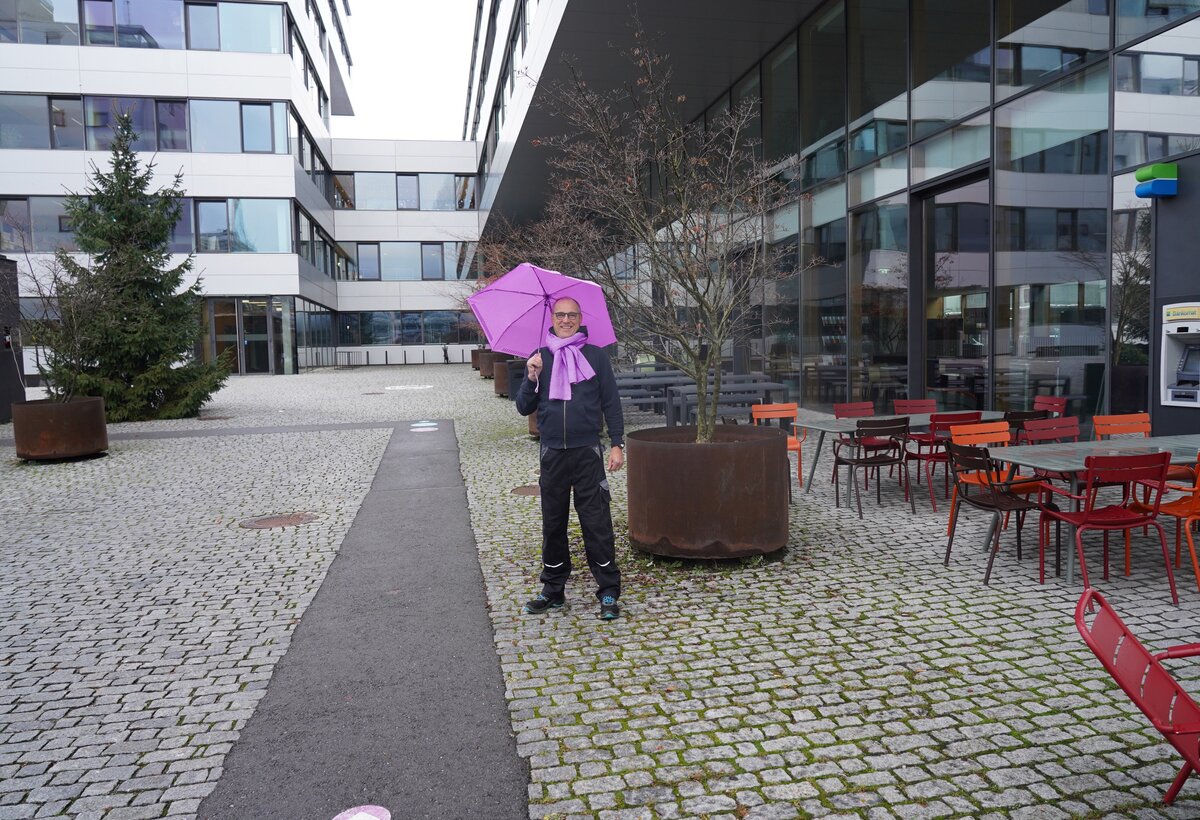 Dieses Bild zeigt den Mitarbeiter Dirk Rautenberg mit lila gesetzten Akzenten vor der FHV.  | © FHV 