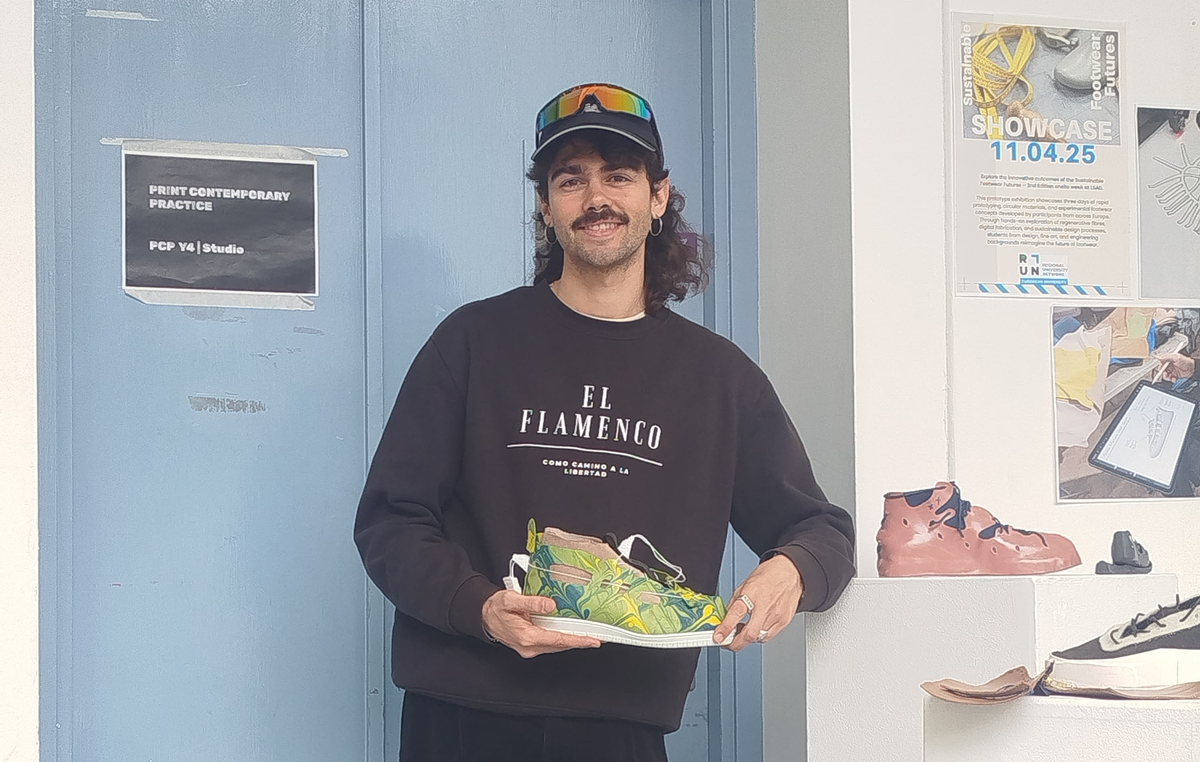 Nacho steht lächelnd da und präsentiert stolz den von ihm selbst entworfenen Schuh. | © Privat