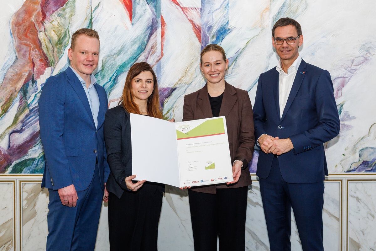 FHV-Mitarbeiterinnen mit der Auszeichnung „Familienfreundlicher Betrieb“, gemeinsam mit dem Landeshauptmann, vor aquarellartigem Hintergrund. | © Land Vorarlberg