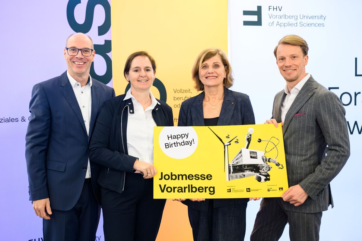 Gruppenfoto von Stefan Fitz-Rankl, Landesrätin Barbara Schöbi-Fink, Regine Kadgien und Simon Kampl. Sie halten ein gelbes Schild der Jobmesse hoch mit "Happy Birthday". | © FHV | Rhomberg