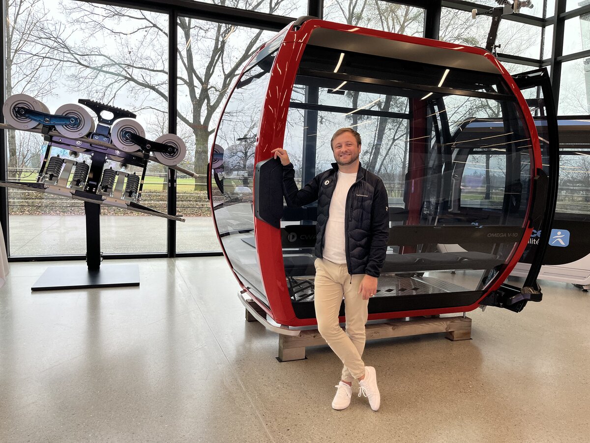 Peter Schwab steht vor einer roten Doppelmayr Gondel im Ausstellungsraum des Unternehmens. | © FHV