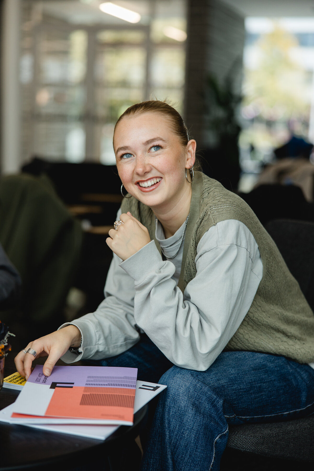 Studentin Hannah lächelt in die Kamera währende sie im Cafe Campus am lernen ist. | © Nina Broell | FHV