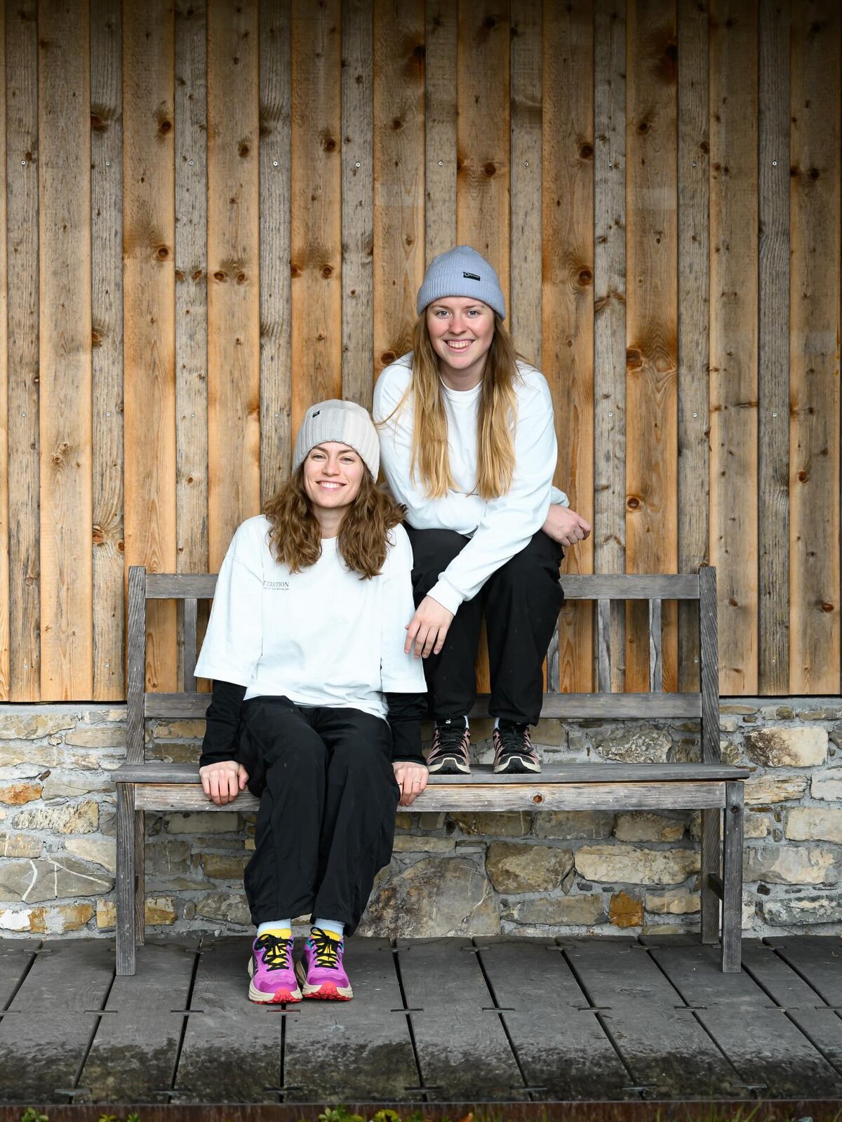 Teresa und Katharina sitzen in einem sportlichen Outfit auf einer Holzbank. | © Jonas Wohlgenannt  