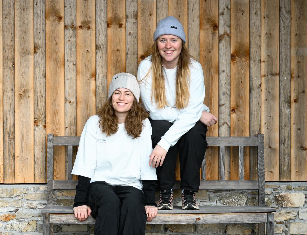 Teresa und Katharina sitzen in einem sportlichen Outfit auf einer Holzbank. | © Jonas Wohlgenannt  