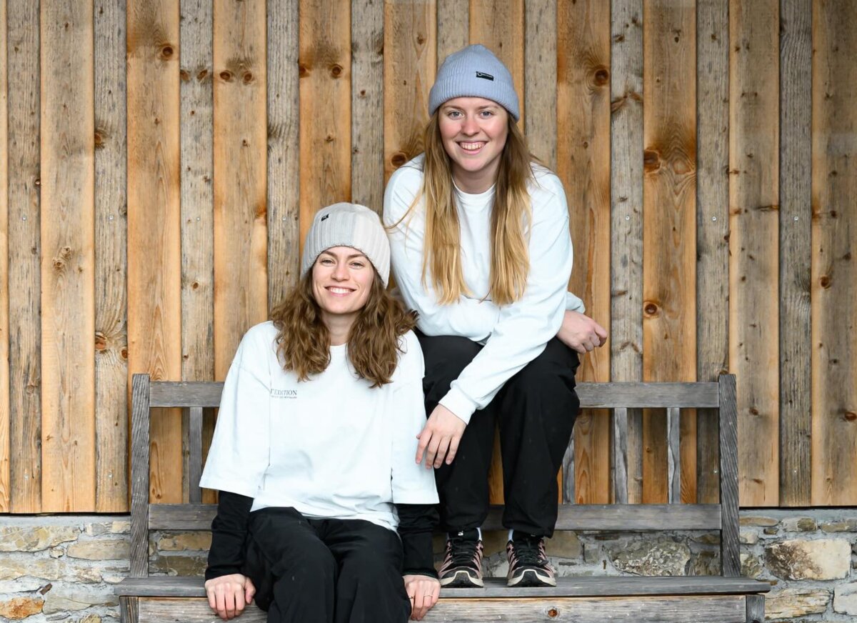 Teresa und Katharina sitzen in einem sportlichen Outfit auf einer Holzbank. | © Jonas Wohlgenannt  