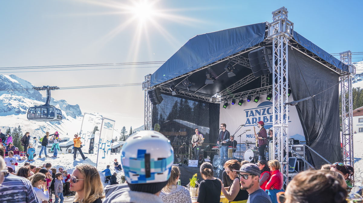 Bühne mit Interpreten vor einer Bergkulisse mit Apres Ski Gästen | © Dietmar Denger - Vorarlberg Tourismus