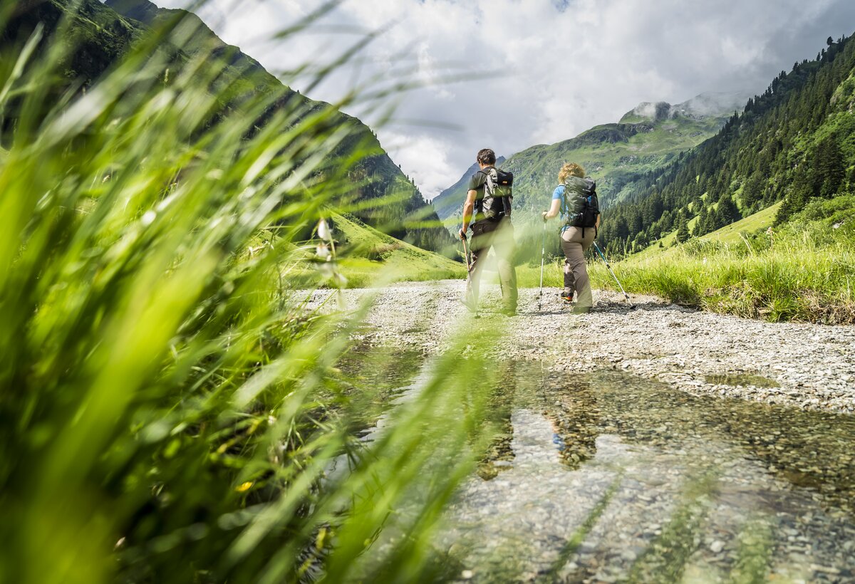 Zwei Wanderer gehen auf einem Weg im Hintergrund Bergkulisse Alpe Garnera | © Dietmar Denger - VorarlbergTourismus