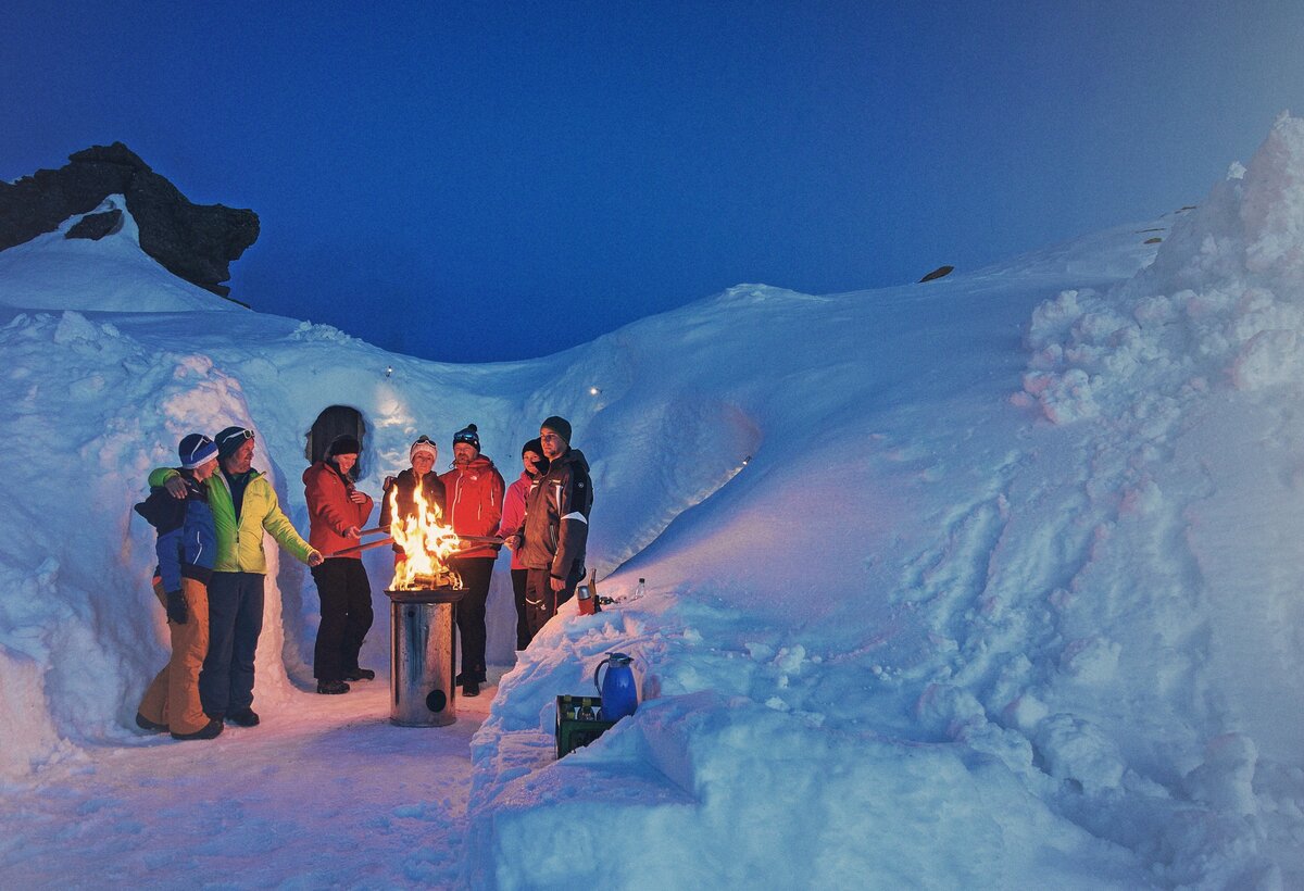 Schneeiglu bei Nacht mit Leuten um ein Lagerfeuer  | © Markus Gmeiner - Vorarlberg Tourismus
