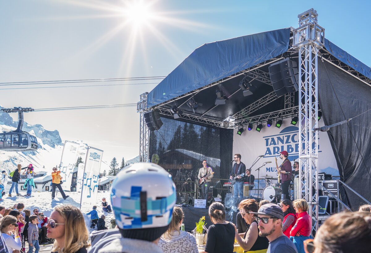 Bühne mit Interpreten vor einer Bergkulisse mit Apres Ski Gästen | © Dietmar Denger - Vorarlberg Tourismus