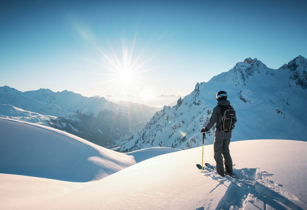 Skifahrer im Tiefschnee inmitten eines Bergpanorama | © Lucas Tiefenthaler - Vorarlberg Tourismus