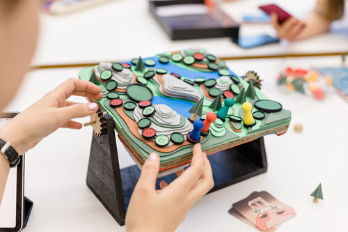 Studierende am Spielbrett entwerfen in der Werkstätte für Analoge Gestaltung | © Nina Broell