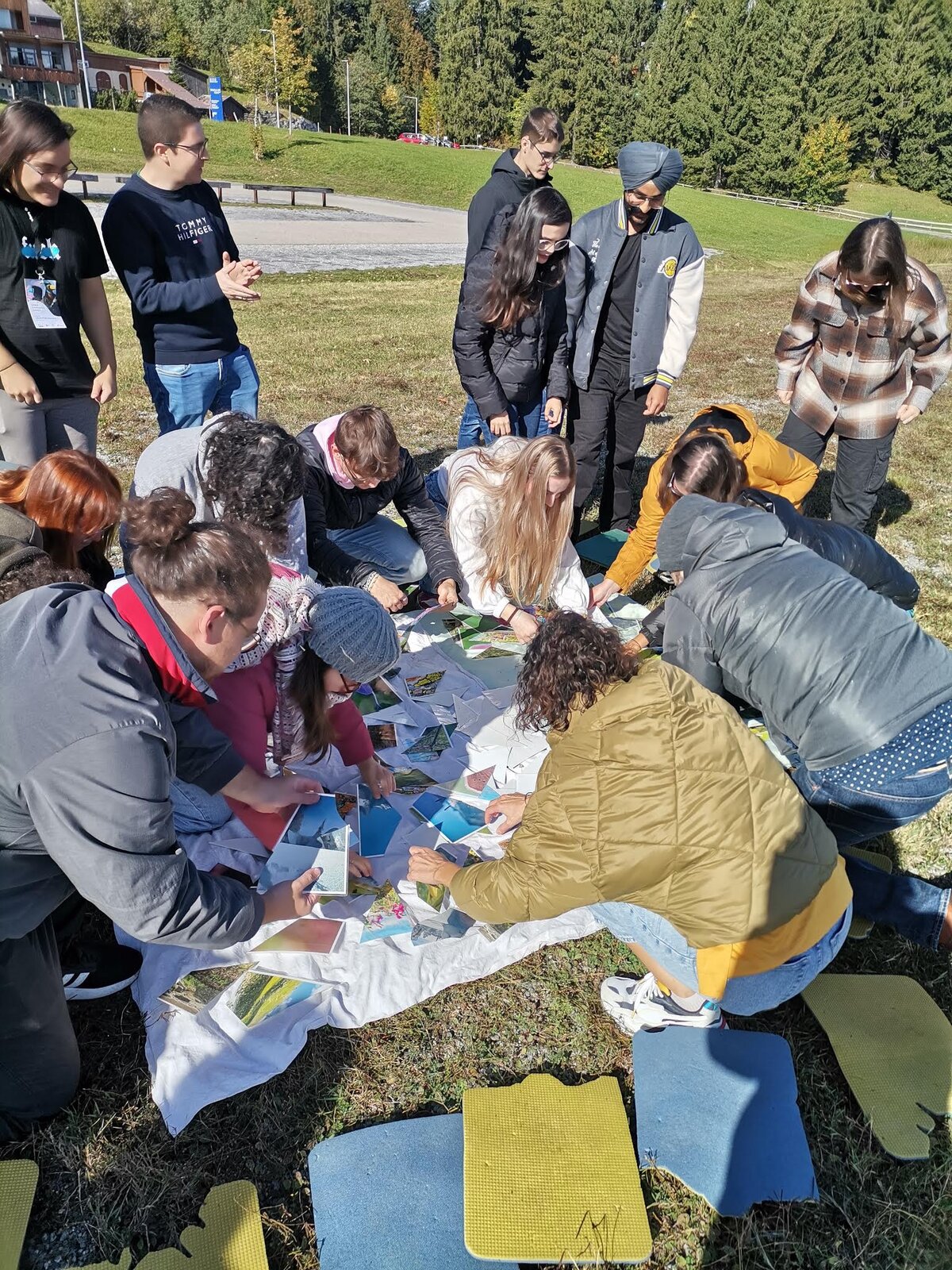 Gruppe Studierender beugt sich über Fotos auf einer Wiese | © ©fachbereich-gestaltung-fhv
